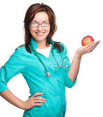 Image showing Young lady doctor is holding a red apple