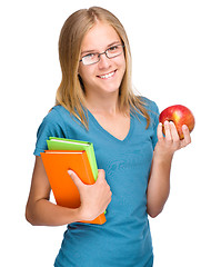 Image showing Young student girl is holding book and apple