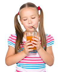 Image showing Little girl is drinking carrot juice