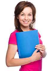 Image showing Young skinny student girl is holding exercise book