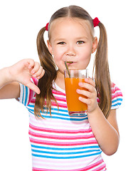 Image showing Little girl is drinking carrot juice