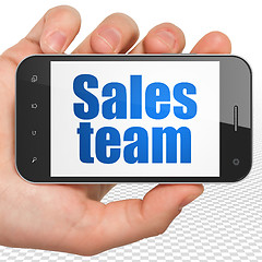 Image showing Marketing concept: Hand Holding Smartphone with Sales Team on display