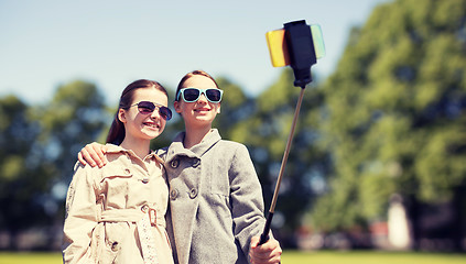 Image showing happy girls with smartphone selfie stick in park