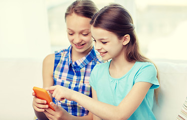 Image showing happy girls with smartphones sitting on sofa