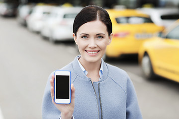 Image showing smiling woman showing smartphone over taxi in city