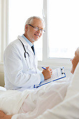 Image showing senior woman and doctor with clipboard at hospital