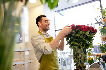 Image showing smiling florist man with roses at flower shop