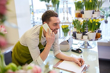 Image showing man with smartphone making notes at flower shop