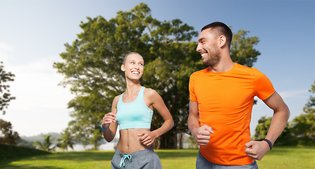 Image showing smiling couple running over summer park background