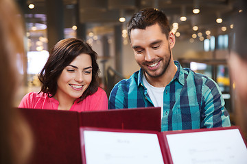 Image showing smiling couple with friends and menu at restaurant