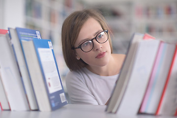 Image showing portrait of famale student selecting book to read in library