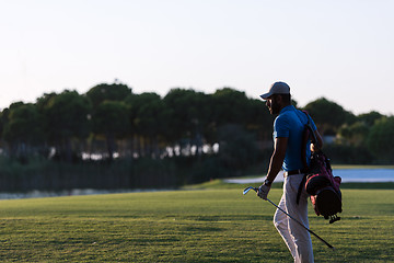 Image showing golfer  walking and carrying golf  bag at beautiful sunset