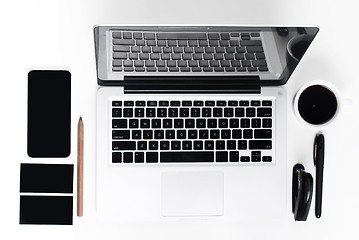 Image showing Business laptop, phone and a coffee on the white table 