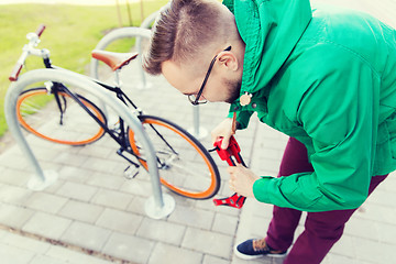 Image showing hipster man fastening fixed gear bike with lock