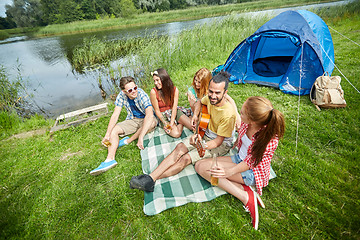 Image showing happy friends with drinks and guitar at camping