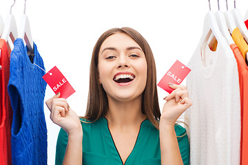 Image showing happy woman with sale tags on clothes at wardrobe