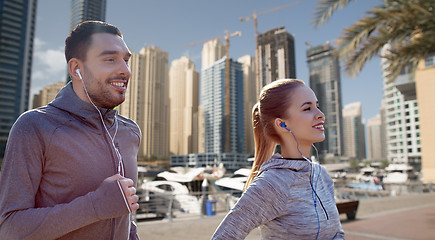 Image showing happy couple with earphones running in city