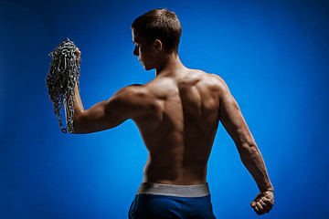 Image showing Muscular guy with chains on his shoulders against a blue wall