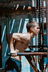 Image showing Muscular guy doing some push ups against the iron chains