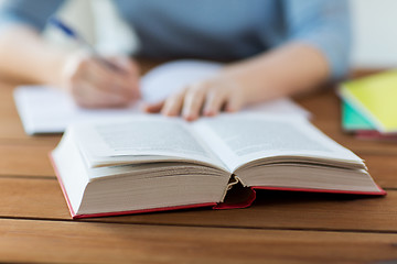 Image showing close up of student with book and notebook at home