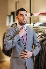 Image showing young man trying suit on in clothing store