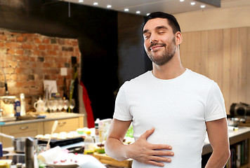 Image showing happy full man touching tummy over kitchen