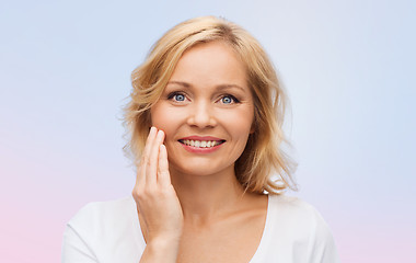 Image showing smiling woman in white t-shirt touching her face