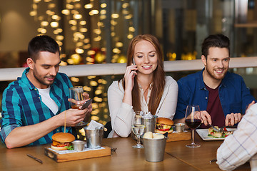 Image showing happy friends with smartphones at restaurant