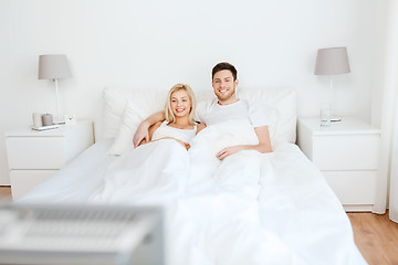 Image showing happy couple lying in bed at home and watching tv