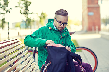 Image showing hipster man with backpack sitting on city bench