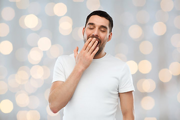 Image showing yawning man over holidays lights background