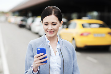 Image showing smiling woman with smartphone over taxi in city