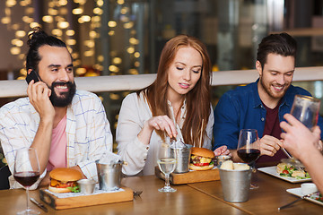 Image showing man with smartphone and friends at restaurant