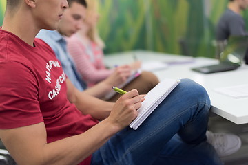 Image showing male student taking notes in classroom