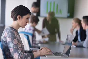 Image showing young business woman at office working on laptop with team on me