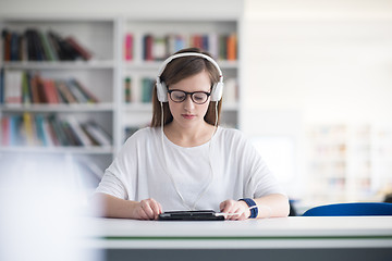 Image showing female student study in library, using tablet and searching for 