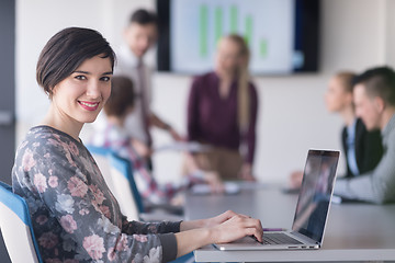 Image showing young business woman at office working on laptop with team on me