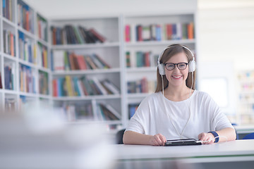 Image showing female student study in library, using tablet and searching for 