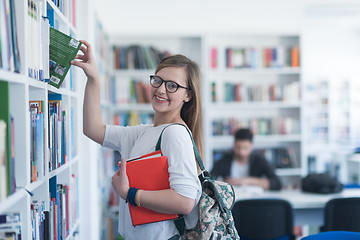 Image showing famale student selecting book to read in library