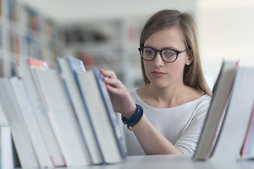 Image showing portrait of famale student selecting book to read in library