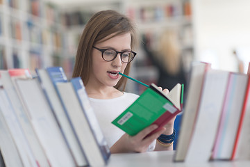 Image showing portrait of famale student selecting book to read in library