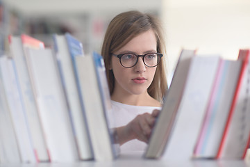 Image showing portrait of famale student selecting book to read in library