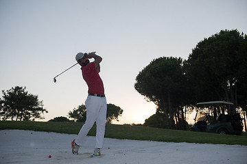 Image showing golfer hitting a sand bunker shot on sunset