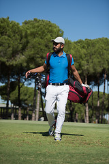 Image showing golf player walking and carrying bag