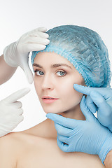 Image showing Plastic surgery concept. Doctor hands in gloves touching the beautiful woman face on white