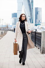 Image showing woman in a light overcoat with a wooden case and a notebook