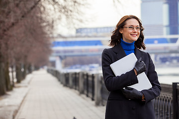 Image showing smiling woman with a laptop outdoors