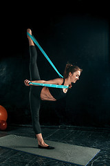 Image showing The brunette athletic woman exercising with rubber tape