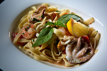 Image showing Fettuccine pasta  with shrimps, lemon, baby octopus, fresh Parmesan cheese, and  oregano. 