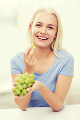 Image showing happy woman eating grapes at home